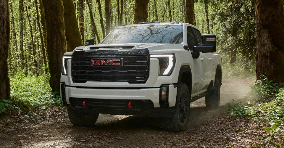 Pick-up pleine grandeur GMC Sierra HD 2024 en mouvement dans une forêt.