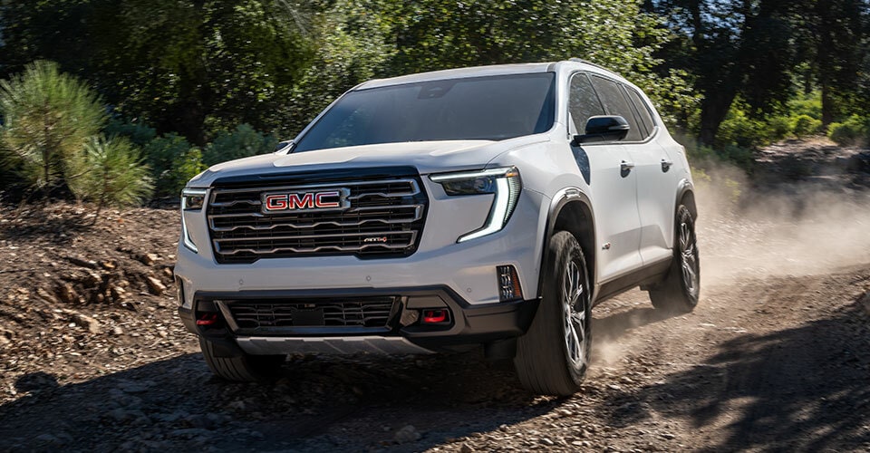 VUS intermédiaire GMC Acadia 2024 stationné sur une route de terre.