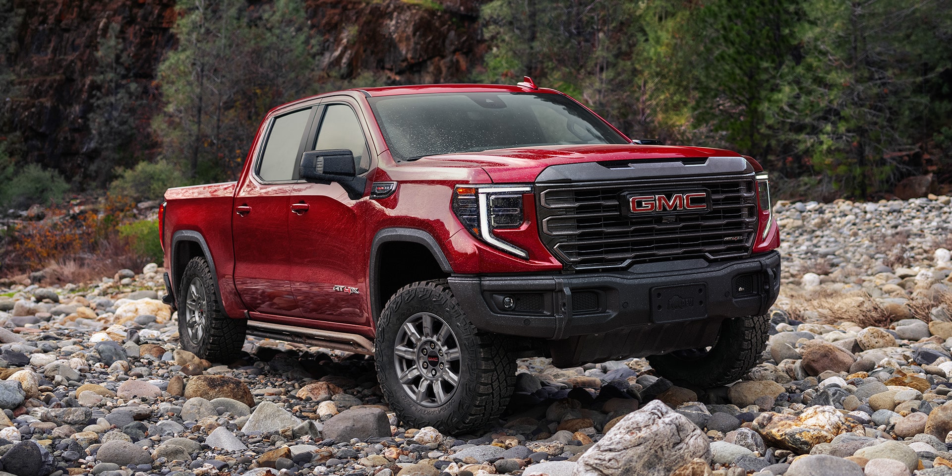 Front Three-Quarters View of the 2026 GMC Sierra AT4X 1500 Pickup Truck Parked on Rocky Terrain.