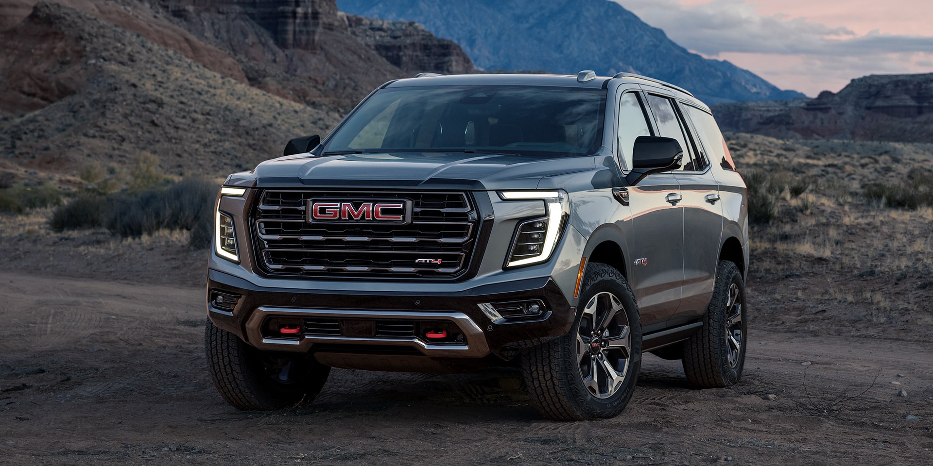 Front Three-Quarters View of the 2026 GMC Yukon AT4X Full-Size Off-Road SUV Parked on a Scenic Field.