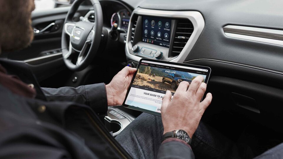 Man using a tablet in a 2022 GMC Acadia.