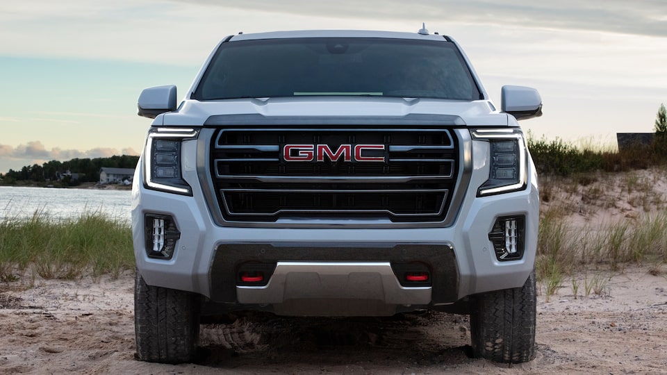 2023 GMC Yukon AT4 driving along a sandy road.