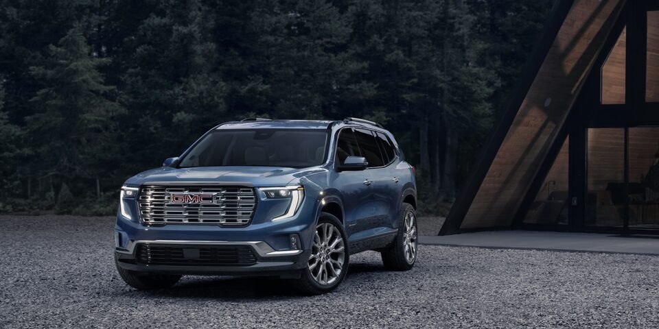 GMC Acadia 2024 stationné sur du gravier près d’une forêt.