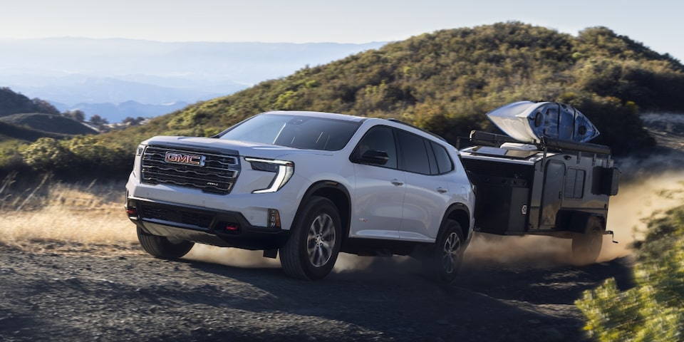GMC Acadia AT4 2024 qui tire une remorque sur un terrain accidenté.