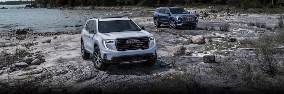 Deux modèles GMC Acadia 2024 stationnés au bord d’un lac.