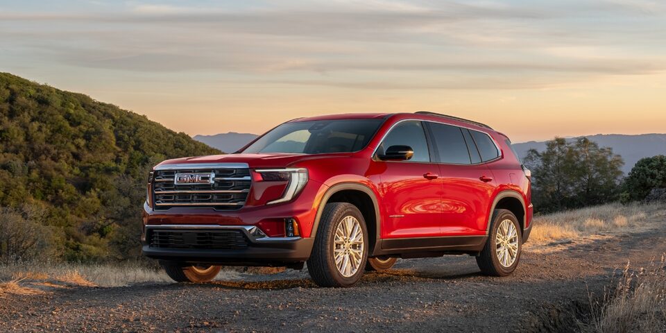 Vue latérale du GMC Acadia Élévation 2024 en mouvement seul sur une route à flanc de montagne.