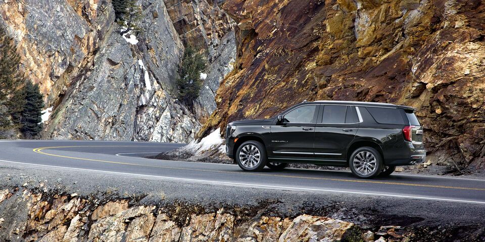 2024 Yukon Denali driving alone on rocky mountain road.