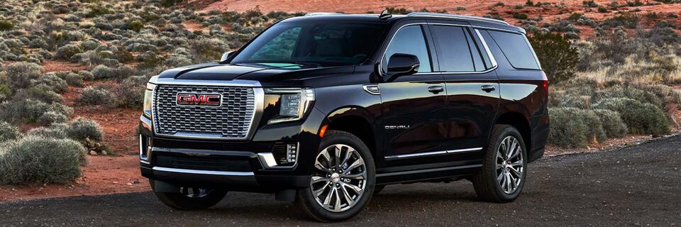 2024 GMC Yukon Denali driving on a desert road.