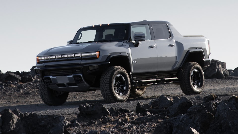 Vue latérale avant du camion GMC Hummer EV 2025 stationné dans les montagnes.