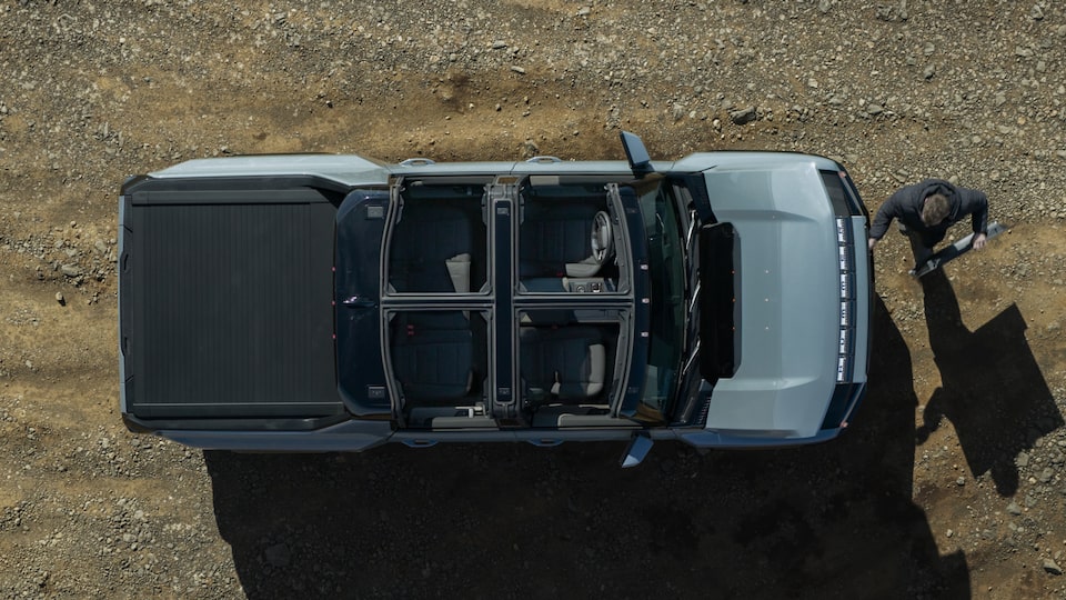 Vue aérienne du GMC Hummer EV 2025 pendant qu’une personne met les panneaux de toit transparent dans le coffre avant.