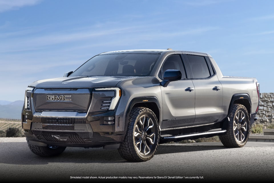Vue latérale avant du GMC Sierra EV 2025 stationné sous un beau ciel bleu.