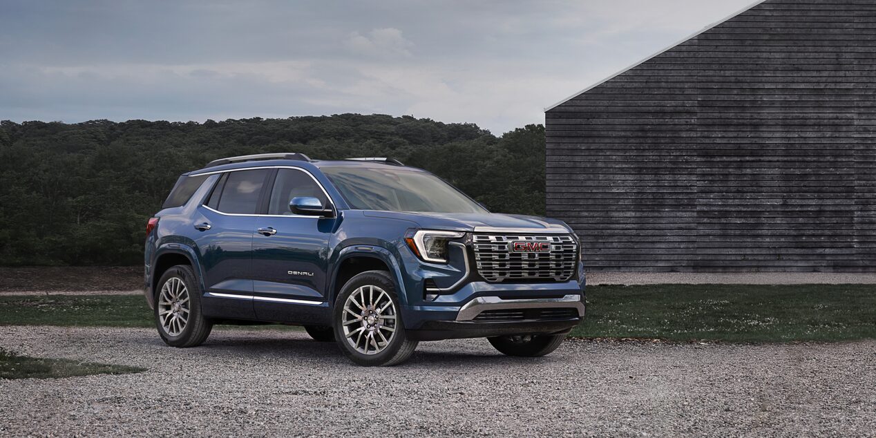 Front-side view of the 2025 GMC Terrain parked outdoors near a wooden building.