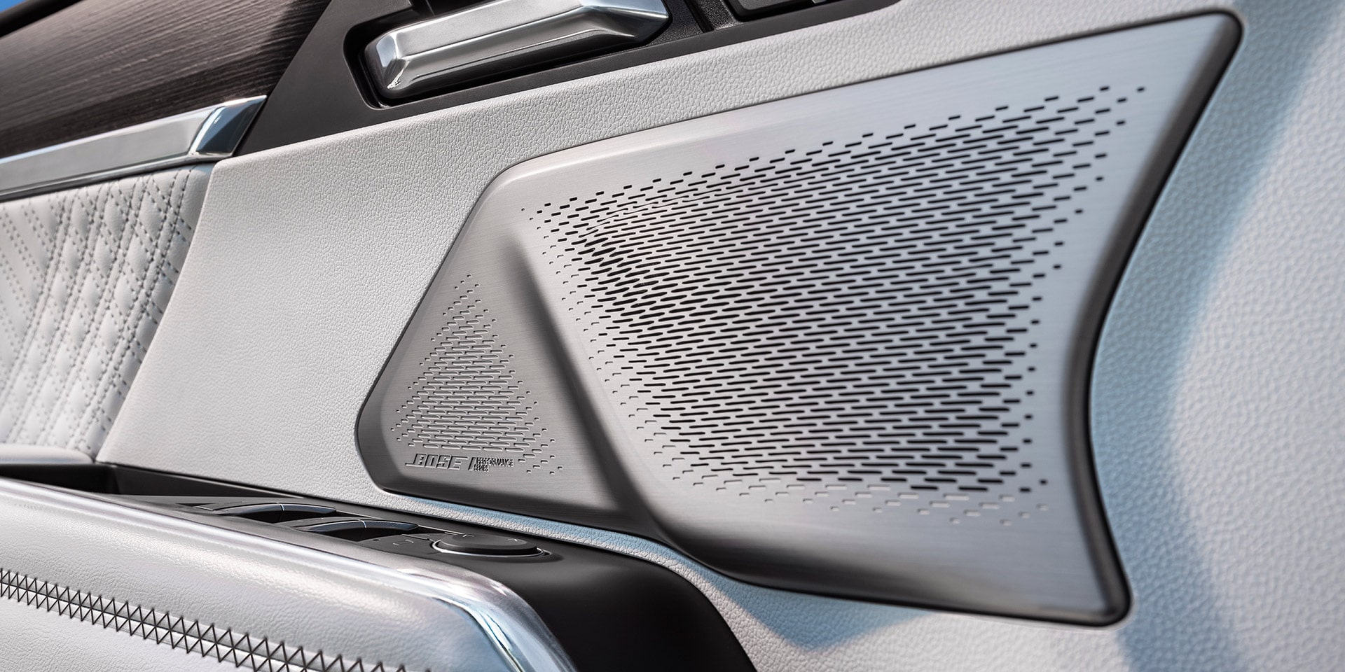 Un gros plan sur la calandre d’un haut-parleur Bose avec une garniture argentée à l’intérieur d’un VUS GMC Acadia 2027.