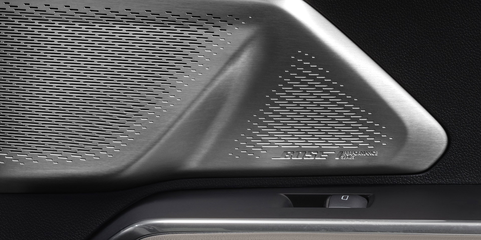 Un gros plan sur la calandre d’un haut-parleur Bose avec une garniture argentée à l’intérieur d’un VUS GMC Acadia 2027.