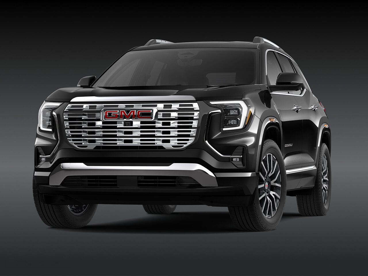 A Front Three-Quarter View of the Black 2026 2027 GMC Terrain Denali SUV on a Dark Background.