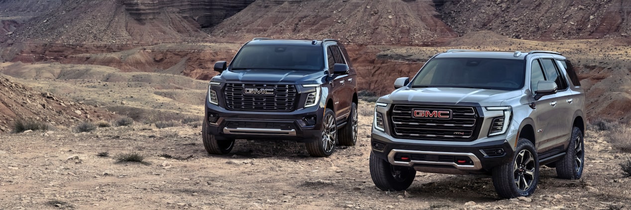 Two 2025 GMC Yukon SUVs parked on a canyon.