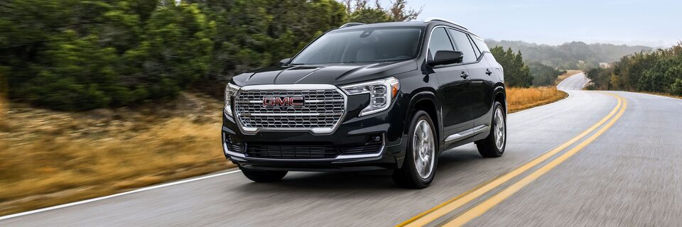 The 2024 GMC Terrain Denali driving on the road showcasing its exteriors.