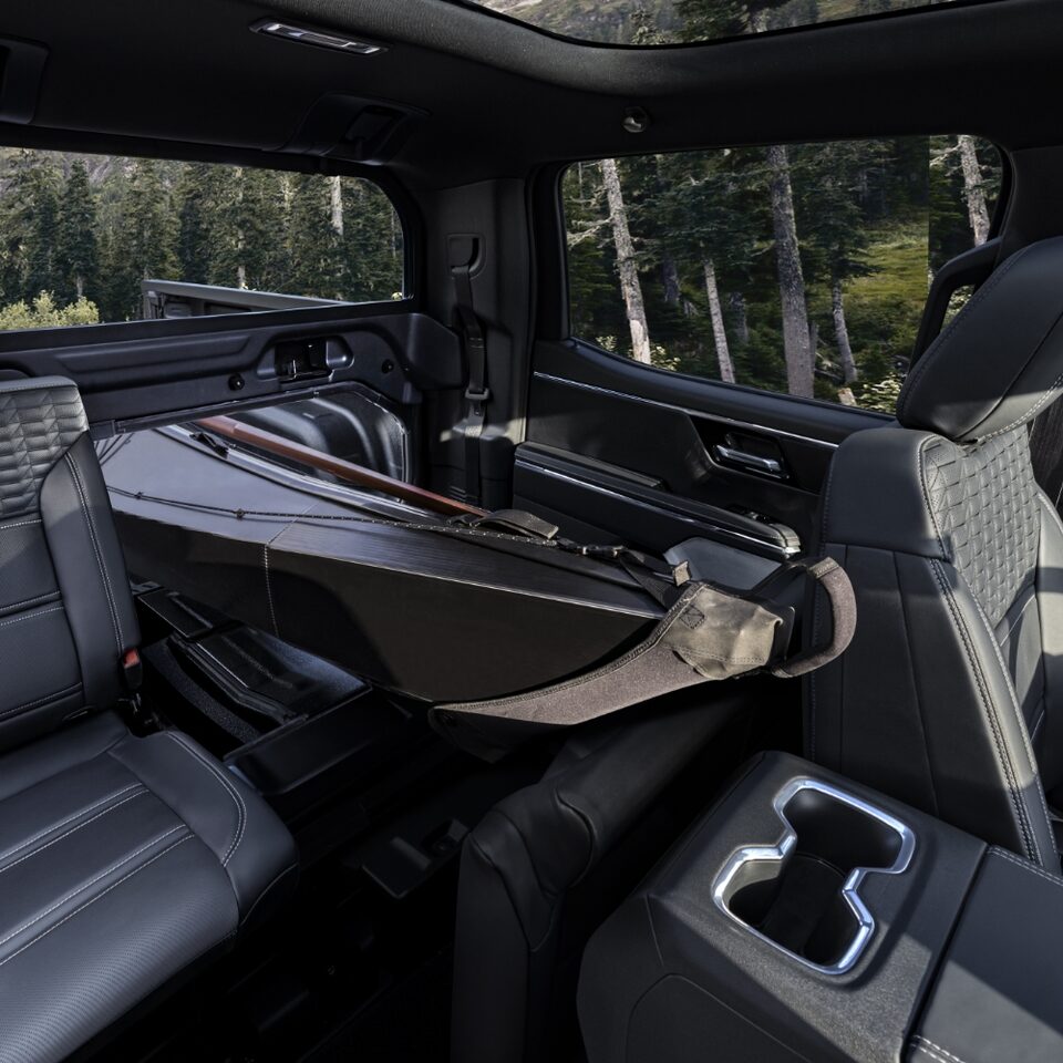 Vue de l’intérieur du GMC Sierra EV Denali avec des sièges abaissés pour transporter un kayak.