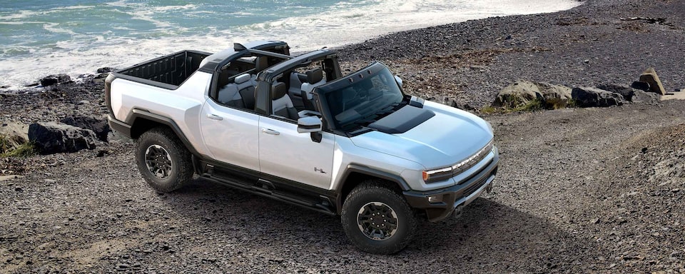 Convertible GMC Hummer EV parked off-road.