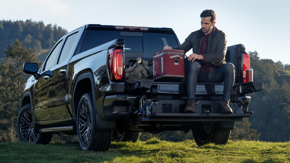 Man sitting on the tailgate of a 2022 Sierra 1500 Denali Ultimate.