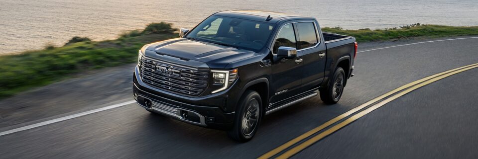 2022 Sierra Denali Ultimate driving down a road at dusk.