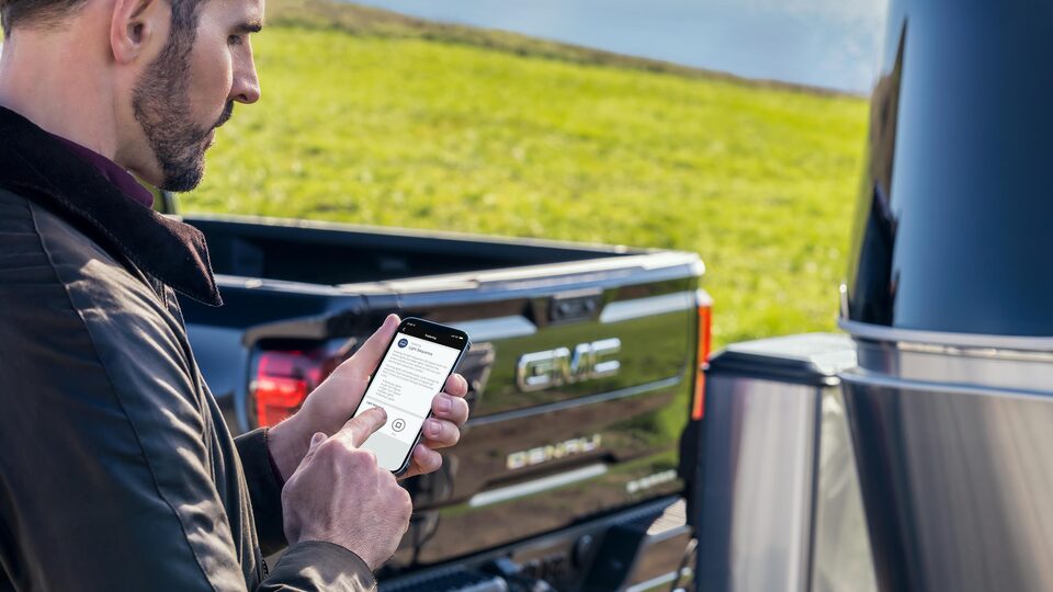 Sierra 1500 Denali 2023 avec une personne qui utilise l’appli mobile myGMC.