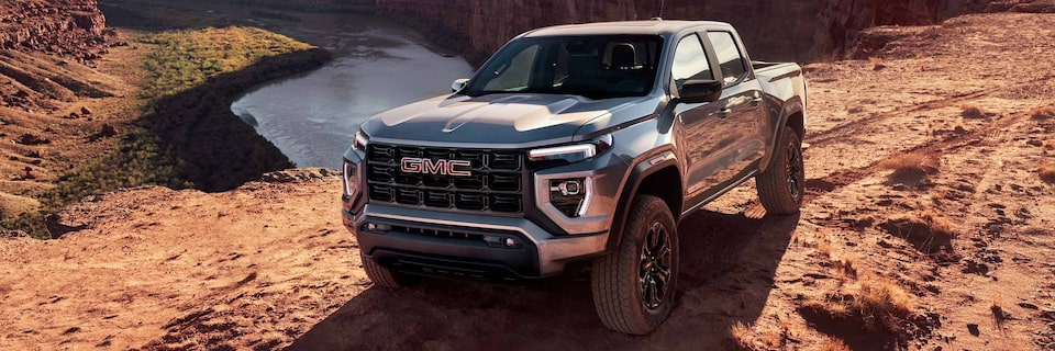 Vue latérale avant du GMC Canyon 2025 en mouvement devant un canyon.