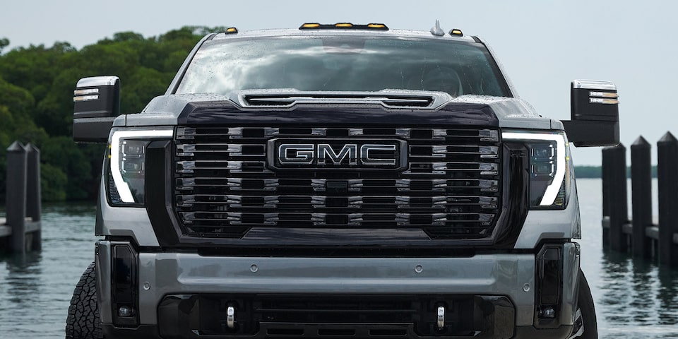 Vue avant du camion GMC Sierra HD 2025 avec les phares allumés.