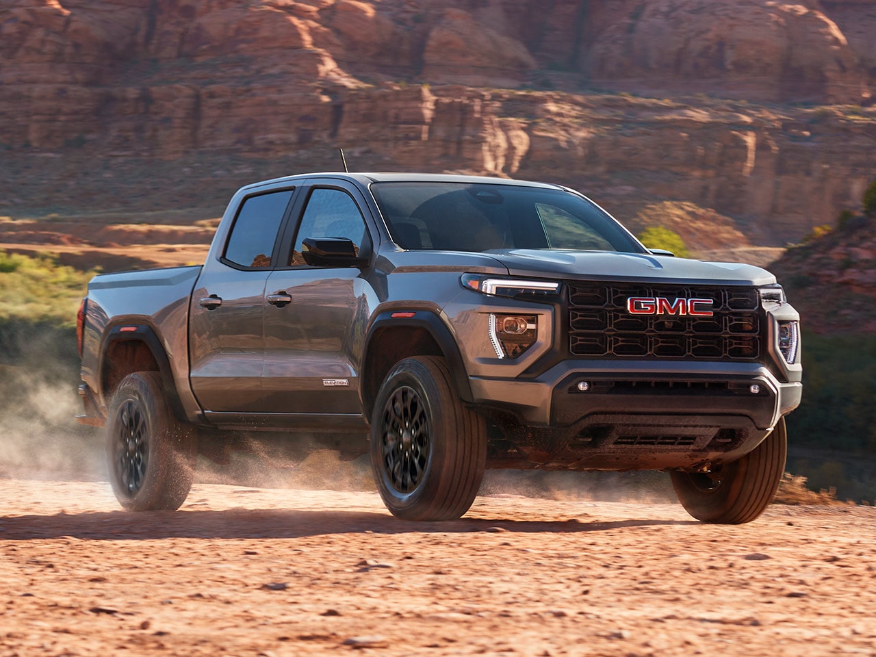 Front-side view of the 2026 GMC Canyon Elevation skidding on a dusty terrain.