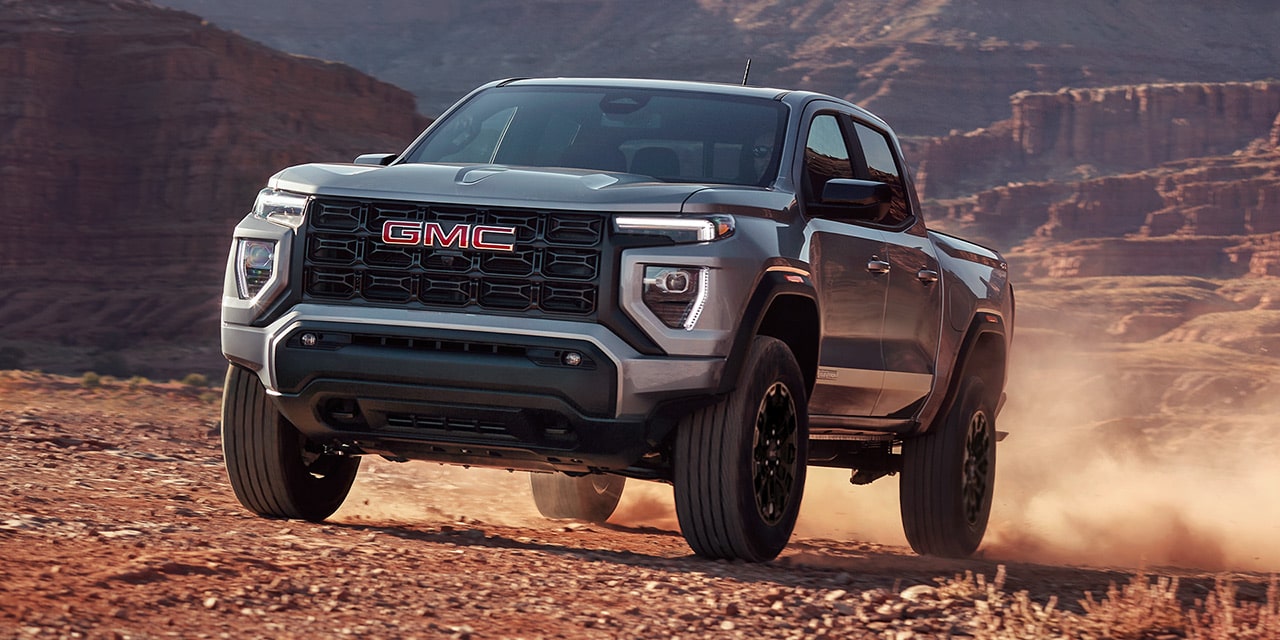 Front-side view of the 2026 GMC Canyon Elevation driving on a dusty terrain.