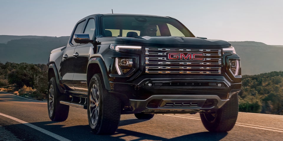 2024 GMC Canyon Denali luxury pickup truck driving on the road.