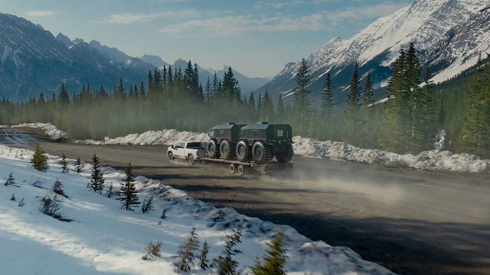 The 2024 GMC Sierra HD towing a trailer down a highway.