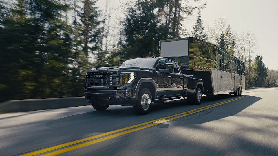 The 2024 GMC Sierra HD towing a trailer down a highway.