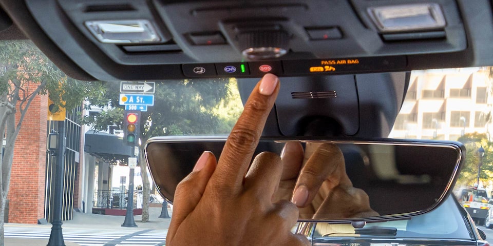 A person pressing the OnStar button on a GMC vehicle.