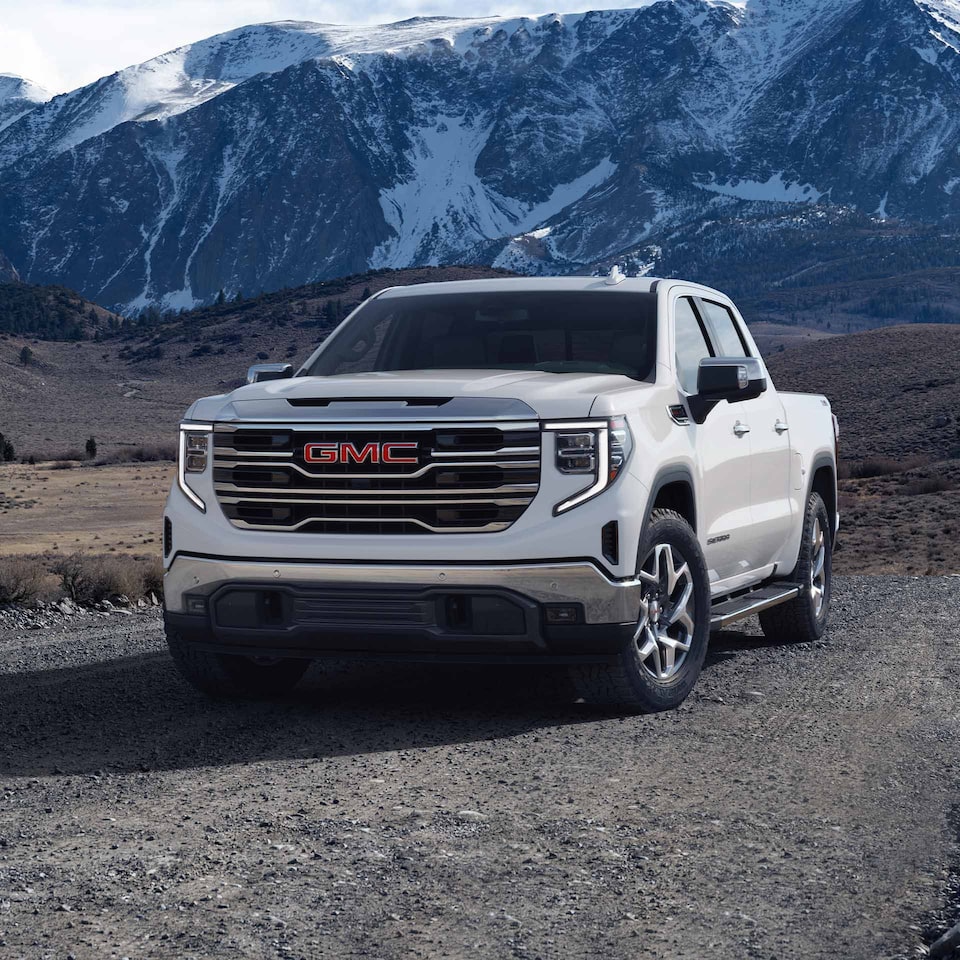 The 2024 GMC Sierra 1500 parked on a stony terrain by the mountainside.
