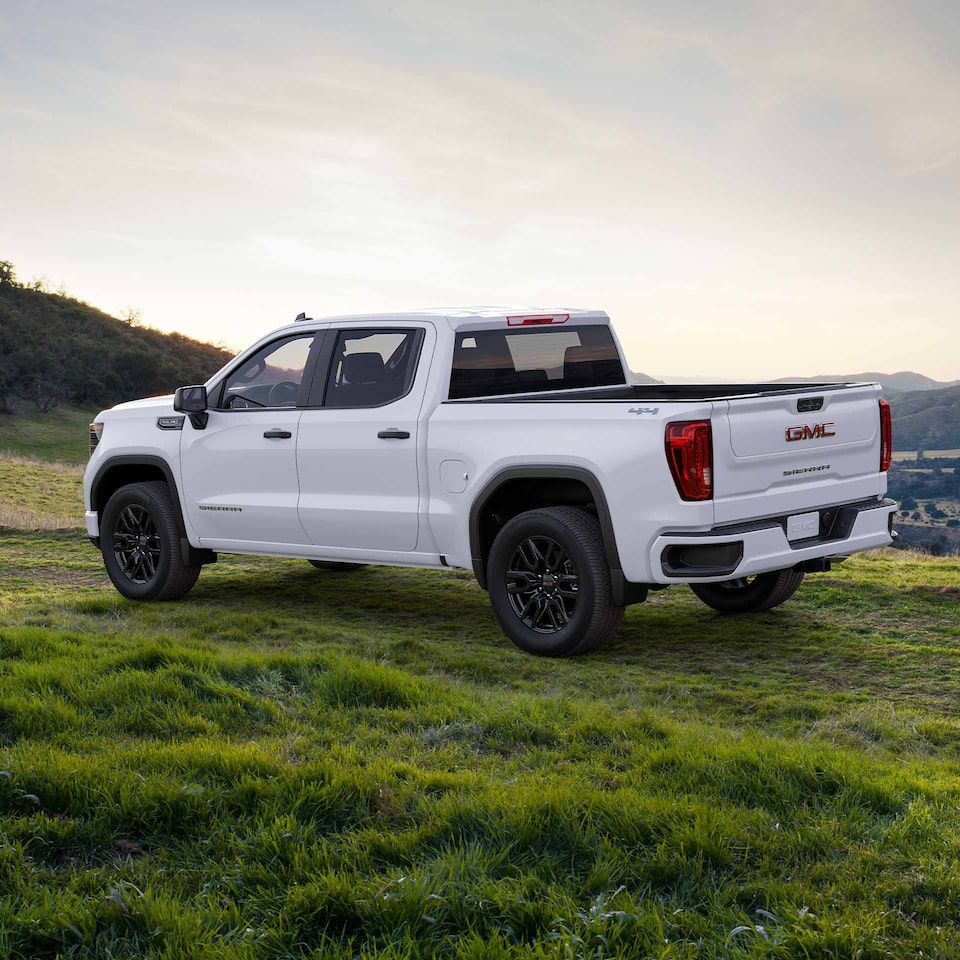 Le GMC Sierra 1500 2024 stationné dans un pré au pied d’une colline.