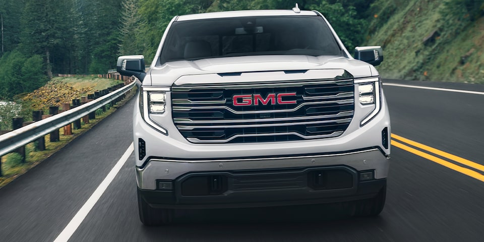 Front view of the 2024 GMC Sierra 1500 SLE driving on the road.