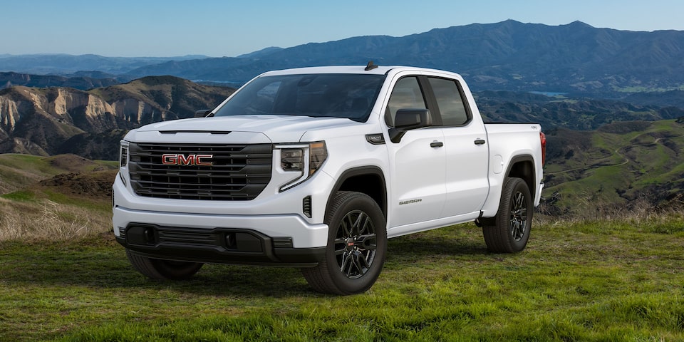 The 2024 GMC Sierra 1500 SLE Graphite Edition parked on a grassy terrain by the hillside.