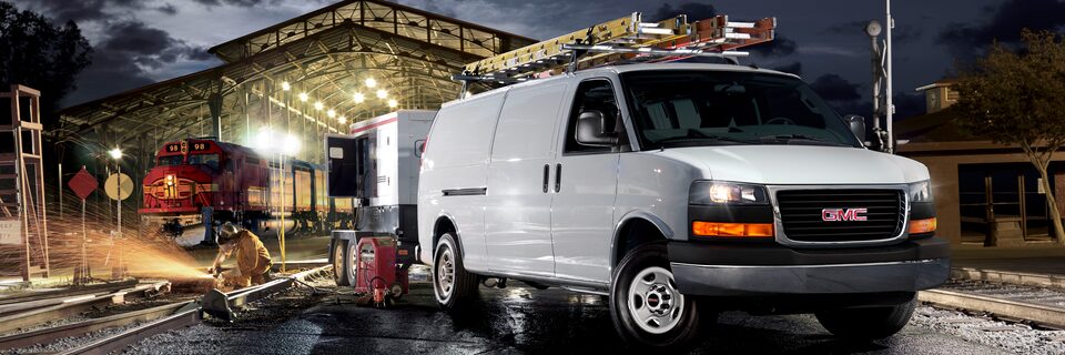 La fourgonnette utilitaire GMC Savana 2023 devant un entrepôt.