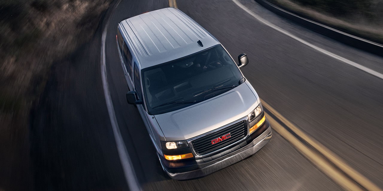Bird's-eye View of a 2026 GMC Savana Cargo Van Driving on an Empty Road at Night.