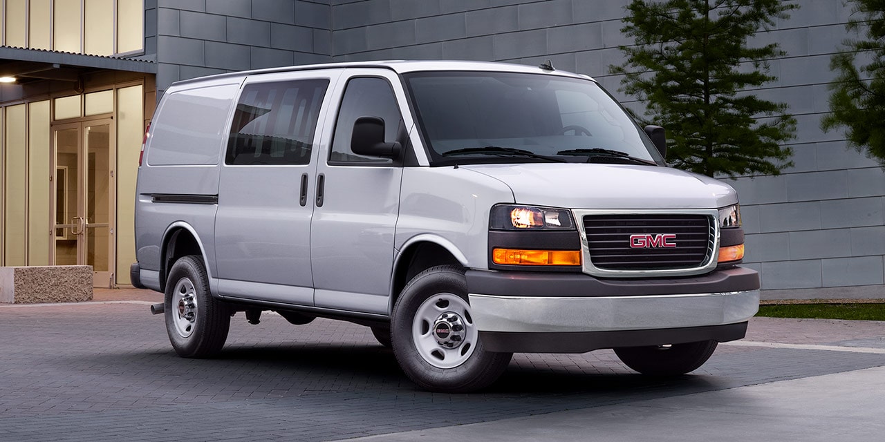 A 2026 GMC Savana Cargo Van Parked on a Paved Area in Front of a Modern Building.