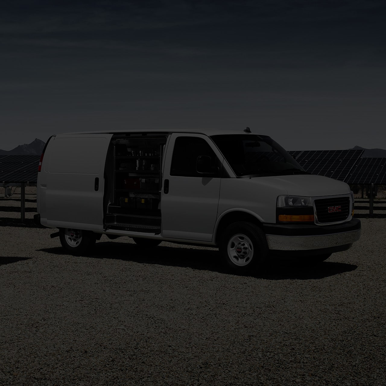 A White 2026 GMC Savana Cargo Van parked outdoors with its Side Door Open.