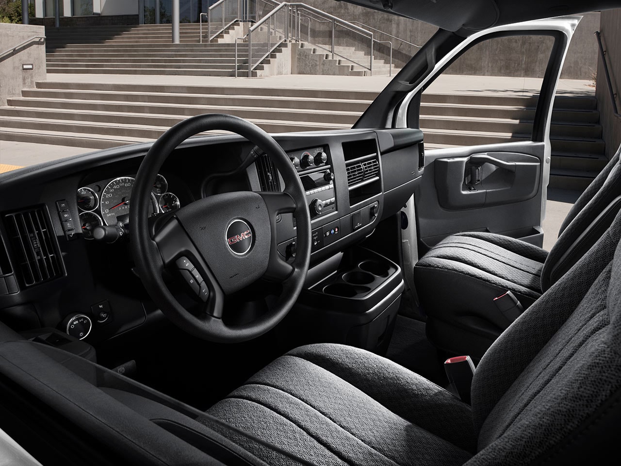 Interior View of the Steering Wheel, Dashboard, and Seating in a 2026 GMC Savana Cargo Van.