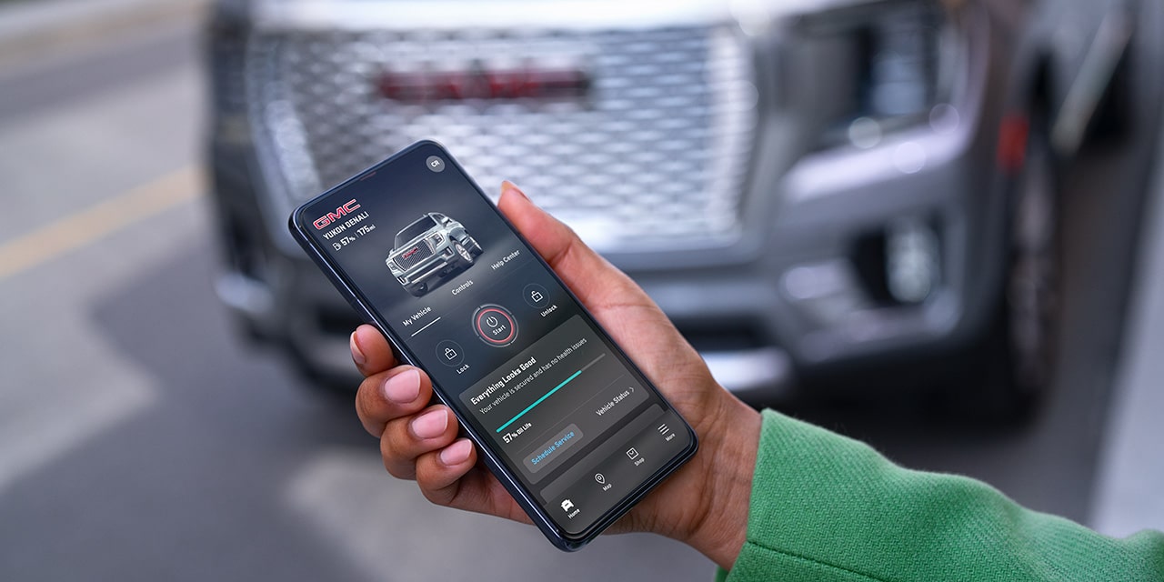 A Person's Hand Holding a Smartphone Displaying vehicle information on the myGMC Mobile App.