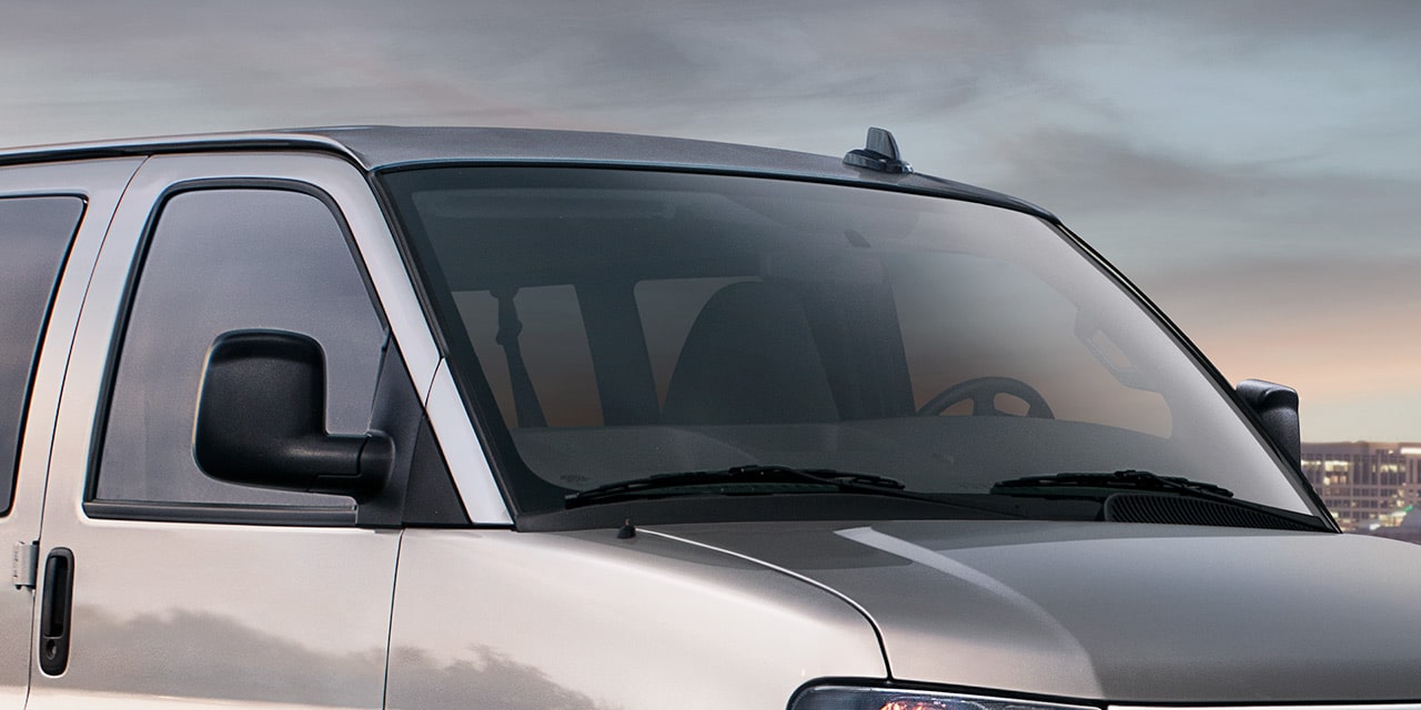 Vue rapprochée du pare-brise et des glaces avant teintées Solar-Ray de la fourgonnette de tourisme GMC Savana 2026.