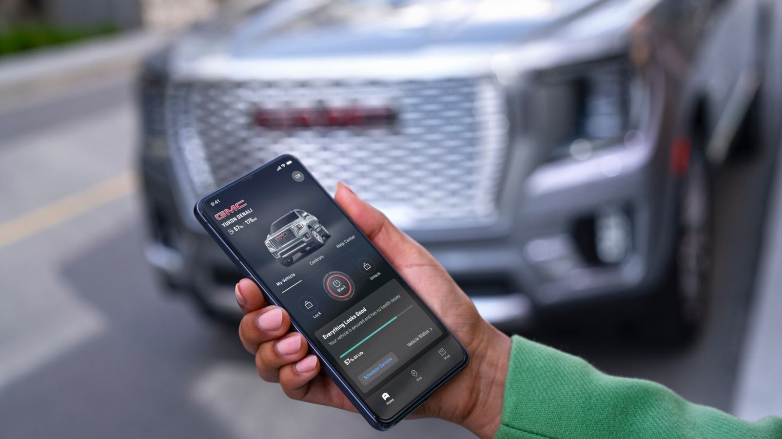 A person using a smartphone near an OnStar-subscribed GMC vehicle.