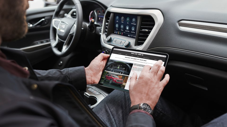 Man using a tablet in a 2023 GMC Acadia.