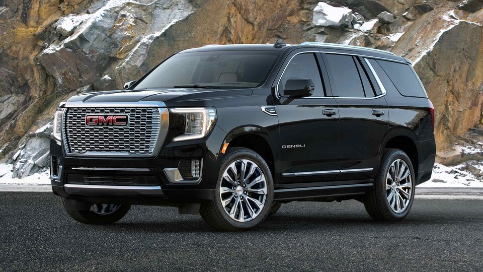 2023 GMC Yukon Denali Ultimate in front of snowy stone backdrop.