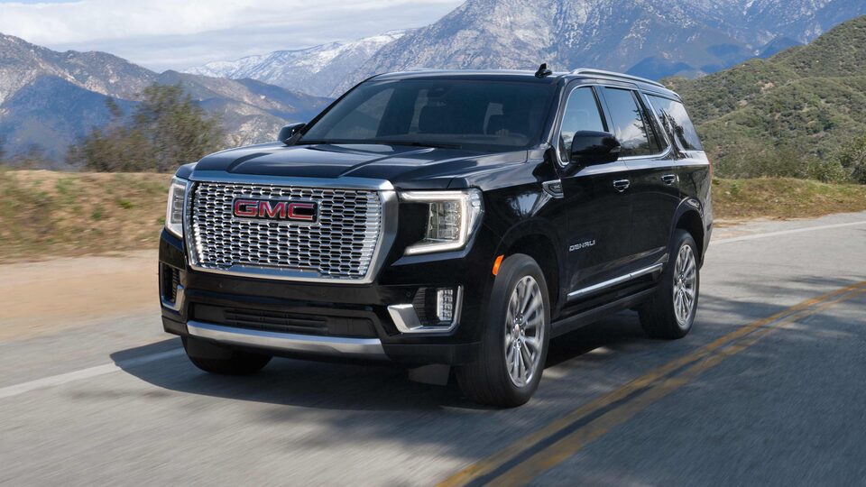 2023 GMC Yukon Denali Ultimate driving through a mountain road.