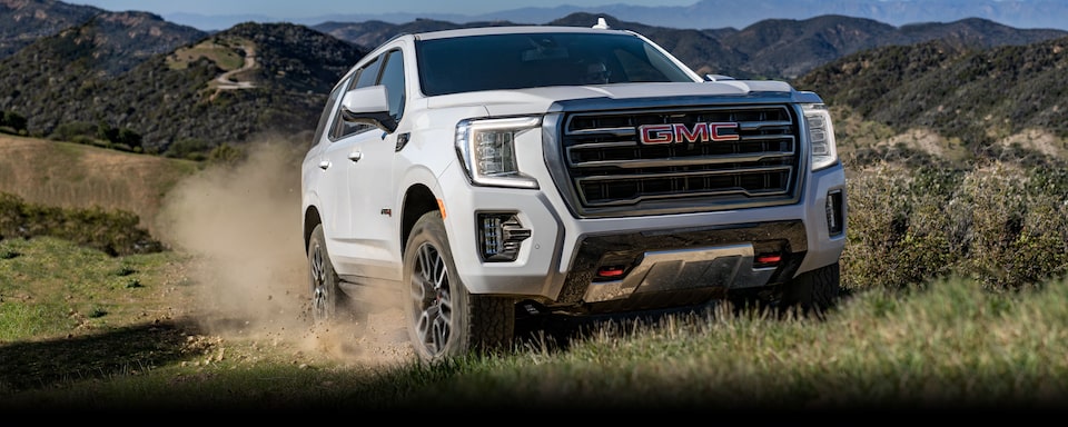 2024 GMC Yukon driving on grassy terrain.